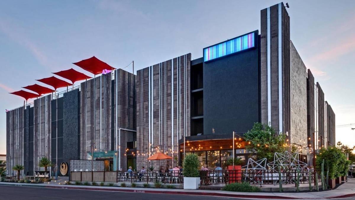 Modern stone and black hotel with red umbrellas and an outdoor patio